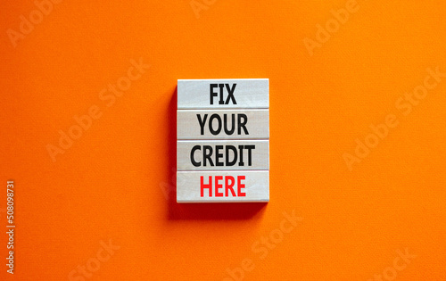 Fix your credit here symbol. Concept words Fix your credit here on wooden blocks on a beautiful orange table orange background. Business, finacial and fix your credit here concept.