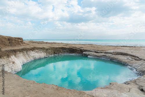 Sinkhole filled with turquoise water, near Dead Sea coastline. Hole formed when underground salt is dissolved by freshwater intrusion, due to continuing sea-level drop. . High quality photo photo