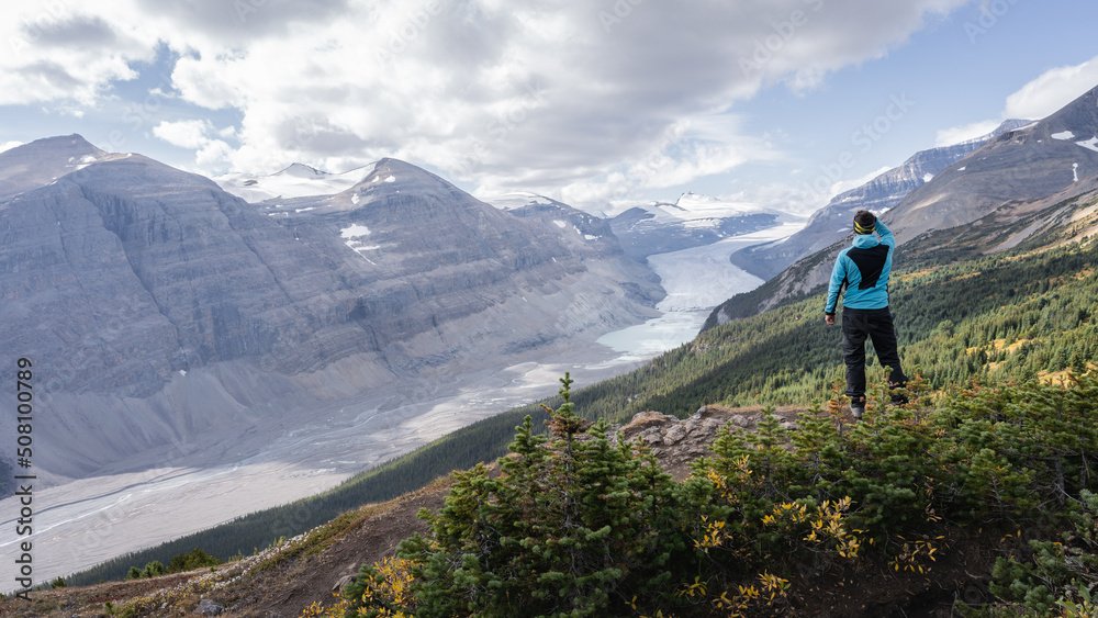 Male hiker overlooking untouched alpine valley with glacier on its end, Jasper, Canada