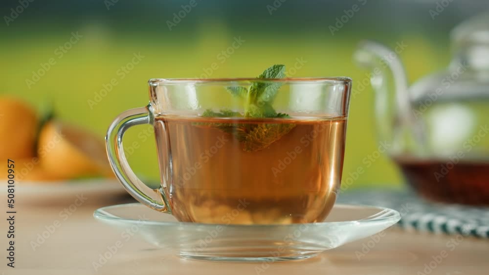 Black tea in cup close-up. Putting mint in tea, healthy morning, detox hot herbal drink. Black tea in cup close-up. Putting mint in tea, healthy morning, detox hot herbal drink.
