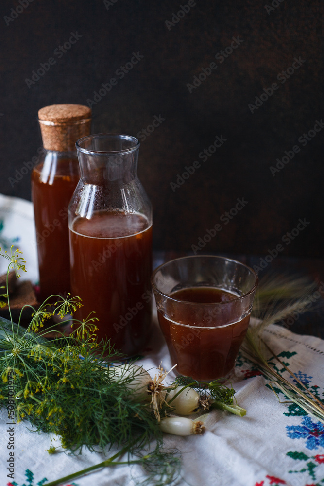 Bottles and a glass of homemade kvass and slices of rye bread with fresh green onion and dill on white towel, traditional Russian drink, traditional folk meal concept. Bottles and a glass of homemade kvass and slices of rye bread with fresh green onion and dill on white towel, traditional Russian drink, traditional folk meal concept.