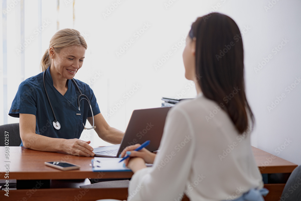 Female patient writes down the doctor's recommendations during appointment in clinic Female patient writes down the doctor's recommendations during appointment in clinic