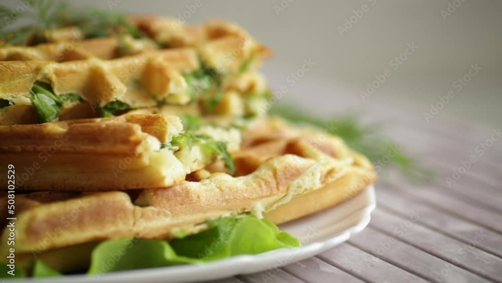 Homemade fried vegetable waffles with herbs inside on a wooden table Homemade fried vegetable waffles with herbs inside on a wooden table