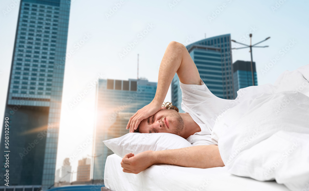 Man in bed and beautiful view of cityscape on background. Poor sleep because of urban noise