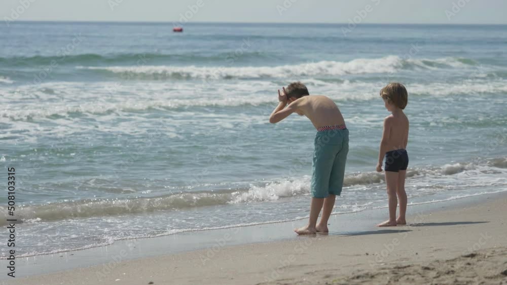 Children with back play with waves going back and forth, waving sea Children with back play with waves going back and forth, waving sea