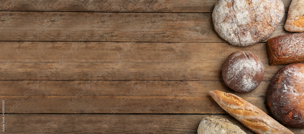 Different kinds of fresh bread on wooden table, flat lay with space for text. Banner design Different kinds of fresh bread on wooden table, flat lay with space for text. Banner design