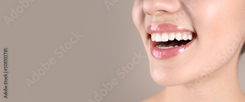 Closeup view of young woman with healthy teeth on beige background, space for text. Banner design photo