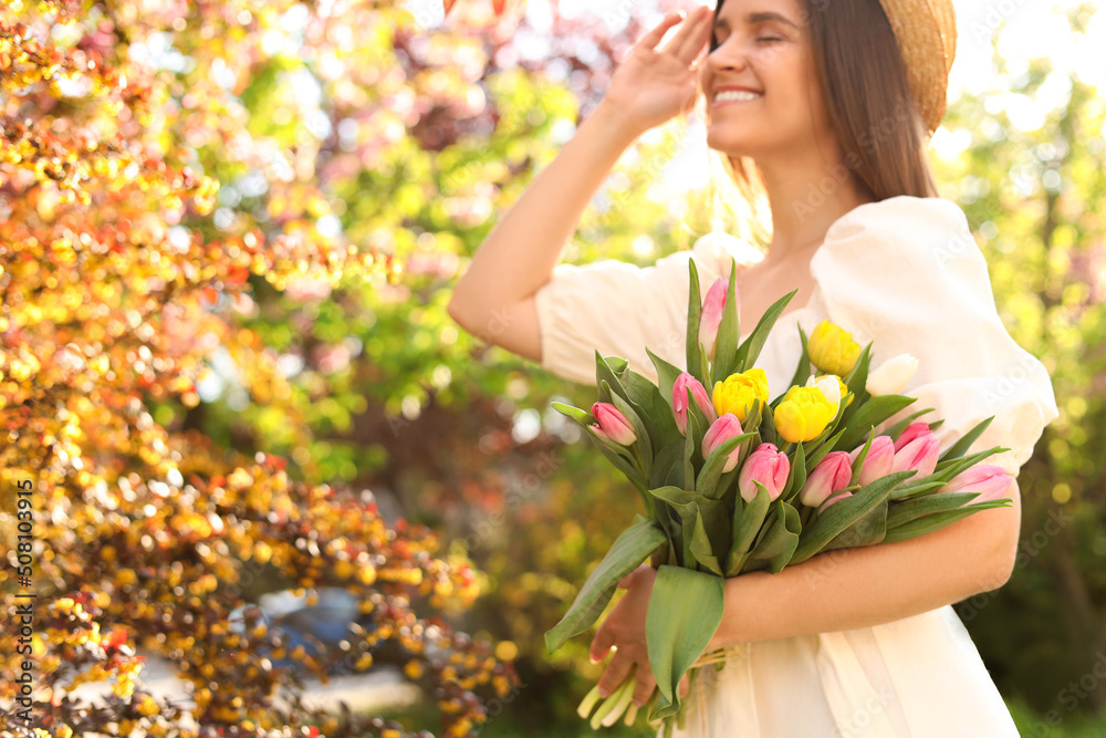 Beautiful young woman with bouquet of tulips in park, focus on flowers. Space for text Beautiful young woman with bouquet of tulips in park, focus on flowers. Space for text