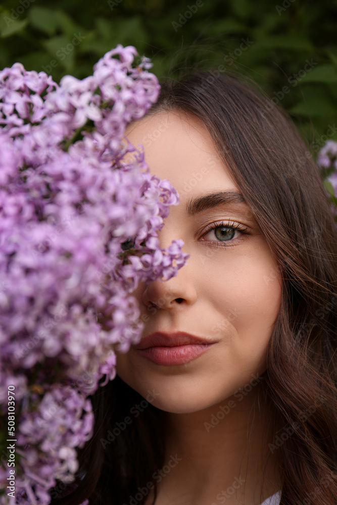 Attractive young woman near blooming lilac bush outdoors, closeup