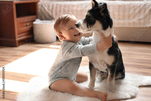 Adorable baby and cute dog on faux fur rug at home photo
