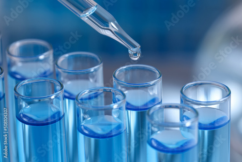 Dripping reagent into test tube on blurred background, closeup. Laboratory analysis