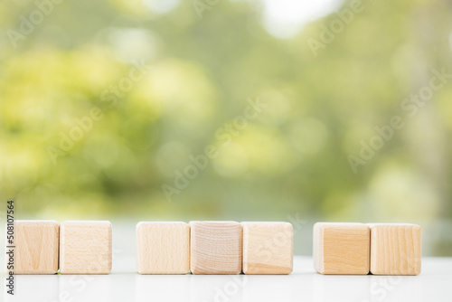 Wooden cubes from natural wood on a green summer background. Copy, empty space for text
