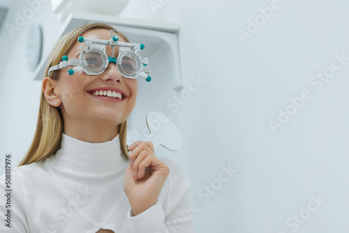 Eye Exam. Woman In Glasses Checking Eyesight At Clinic. Blonde Girl In Optometrist Trial Frame Holding Test Glass At Optometry Diagnostic Center