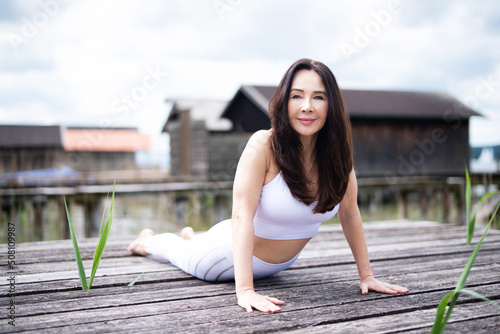 Attraktive Frau beim Yoga im Freien auf einem Steg 