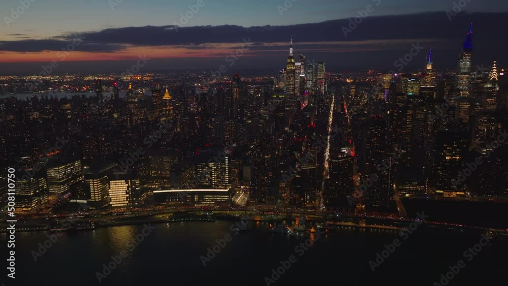 Aerial panoramic view of evening skyline with illuminated skyscrapers. Heavy traffic on waterfront trunk road. Manhattan, New York City, USA Aerial panoramic view of evening skyline with illuminated skyscrapers. Heavy traffic on waterfront trunk road. Manhattan, New York City, USA
