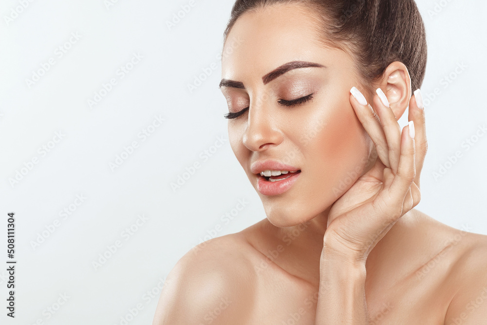 Beautiful smiling woman with healthy smooth facial clean skin applying cosmetic cream and touch own face. Model with  Beauty face. Skin care Moisturizer Facial treatment. Cosmetology. Spa.