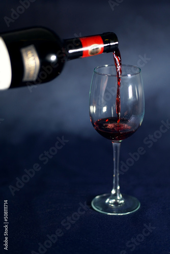 Red wine pouring into a wine glass. Smoke background with grey tonation. photo