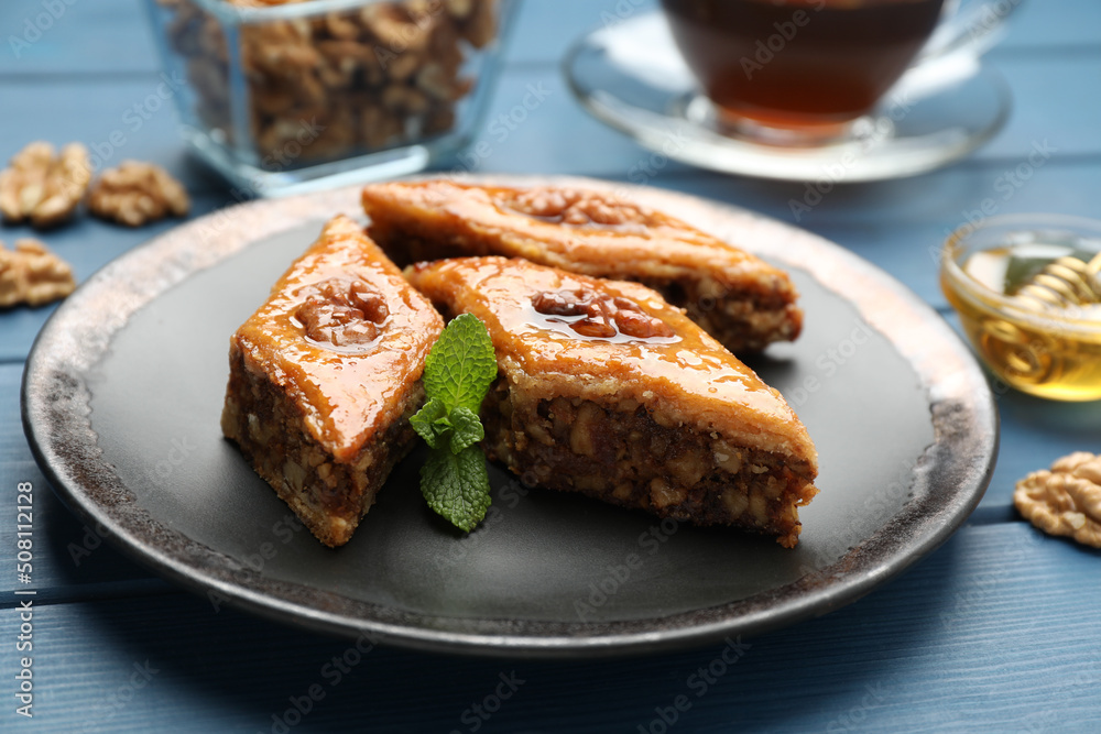 Delicious sweet baklava with walnuts and mint on blue wooden table, closeup