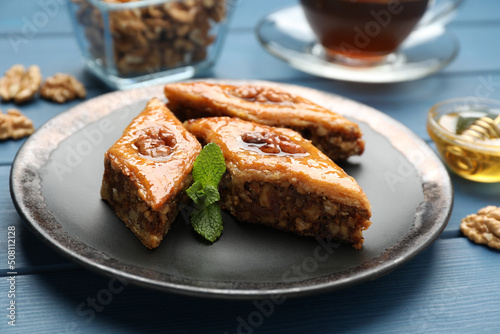 Delicious sweet baklava with walnuts and mint on blue wooden table, closeup