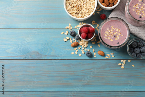 Tasty berry smoothie with oatmeal on light blue wooden table  flat lay. Space for text