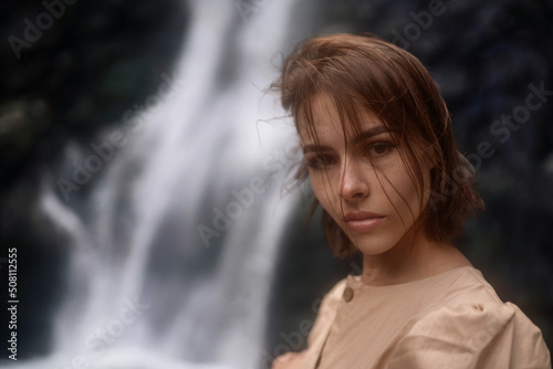 Portrait of a gorgeous woman with short brown hair against the backdrop of waterfall.