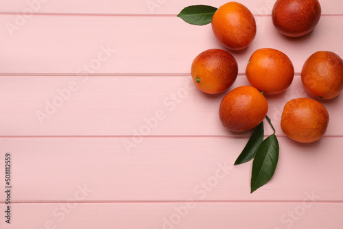 Many ripe sicilian oranges and leaves on pink wooden table, flat lay. Space for text