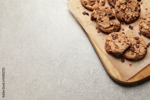 Many delicious chocolate chip cookies on grey table, top view. Space for text