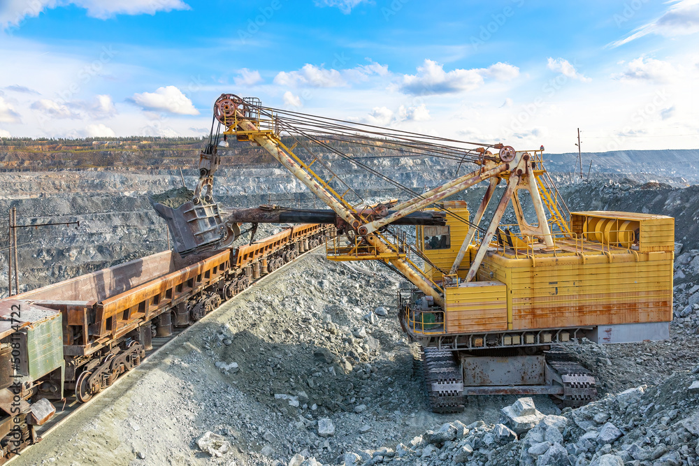 Loading of asbestos on a dumcar. Extraction and transportation of asbestos. Large quarry yellow excavator. Mining works Loading of asbestos on a dumcar. Extraction and transportation of asbestos. Large quarry yellow excavator. Mining works