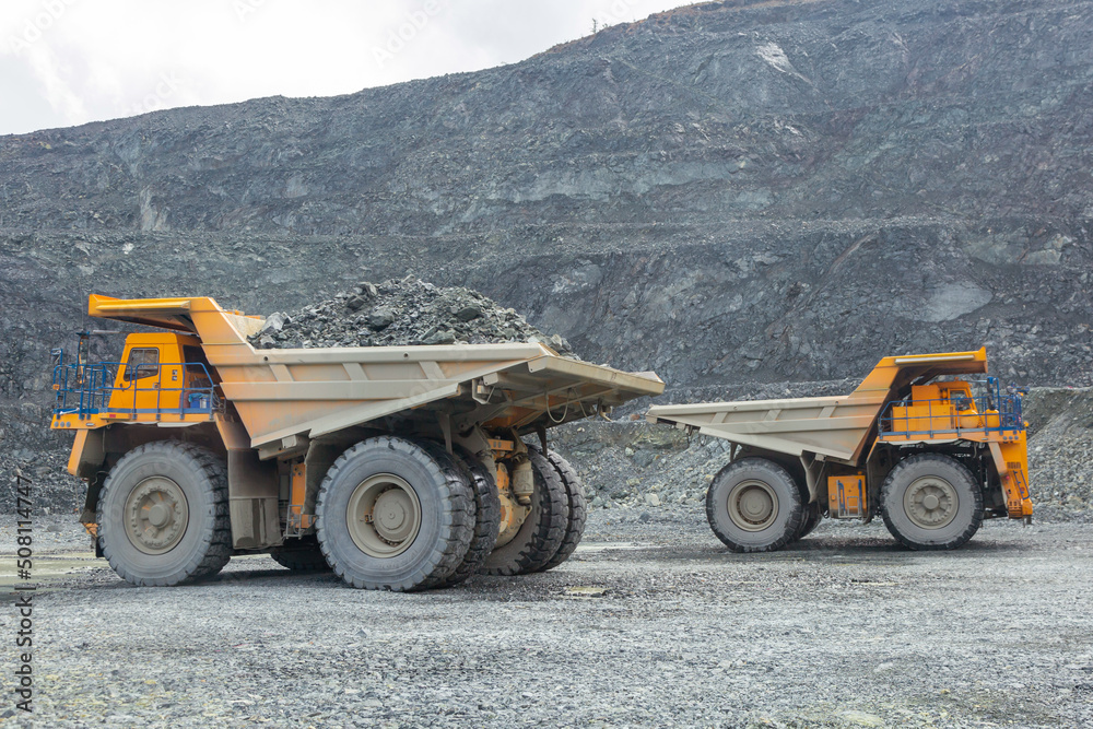 Transportation of copper ore rocks by dump trucks. Large quarry yellow truck. The mining truck drives through the quarry.