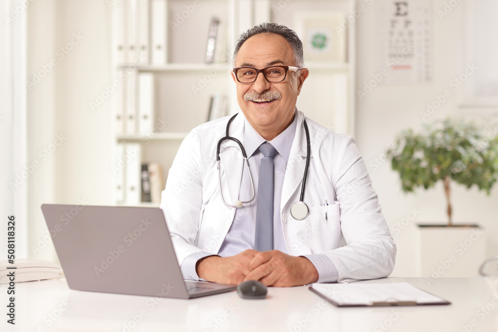Cheerful mature male doctor sitting in an office Cheerful mature male doctor sitting in an office