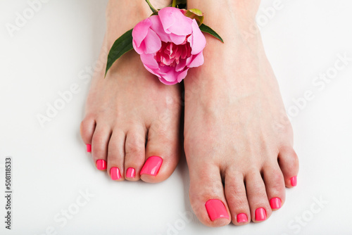 woman with beautiful feet with pedicure and  peony on  white background . Spa concept 