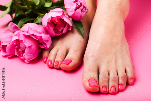 woman with beautiful feet and peony  on  pink background . Spa concept 