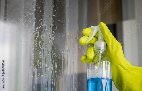 Fotografia A worker sprays window cleaner. close up.