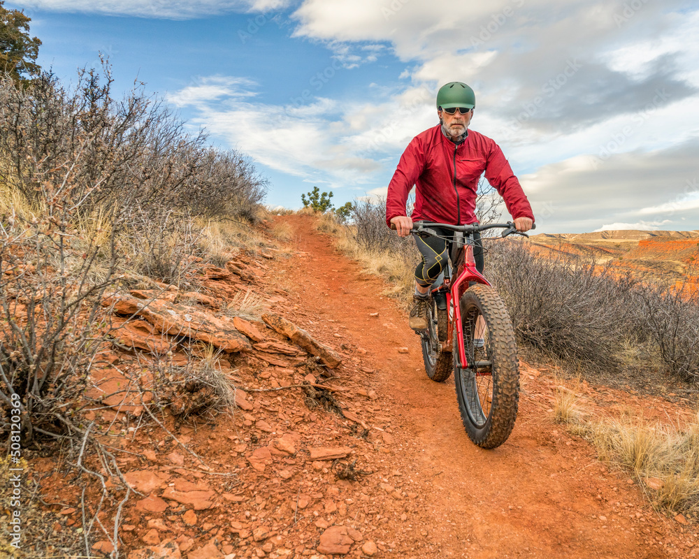 Fototapeta premium a senior male riding a fat mountain bike on a single track trail in Red Mountain Open Space in Colorado, late fall scenery