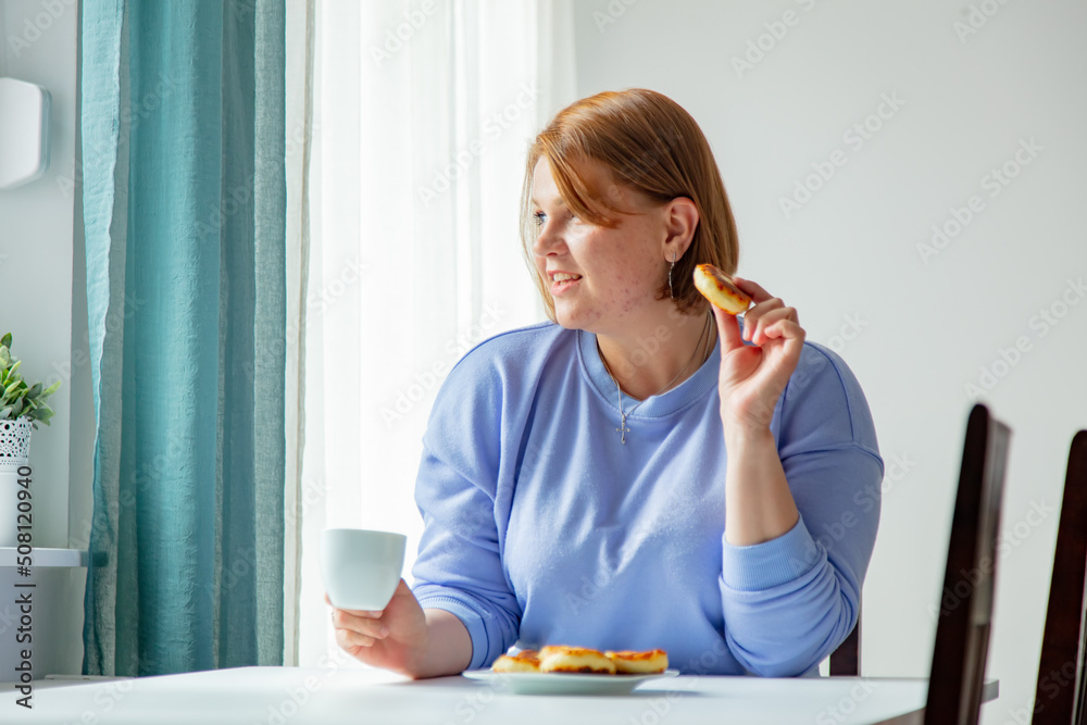 Ukrainian migrant woman sit at table with cup and cheesecakes on breakfast Ukrainian migrant woman sit at table with cup and cheesecakes on breakfast