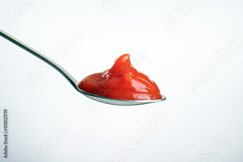 Spoon with ketchup on a light background