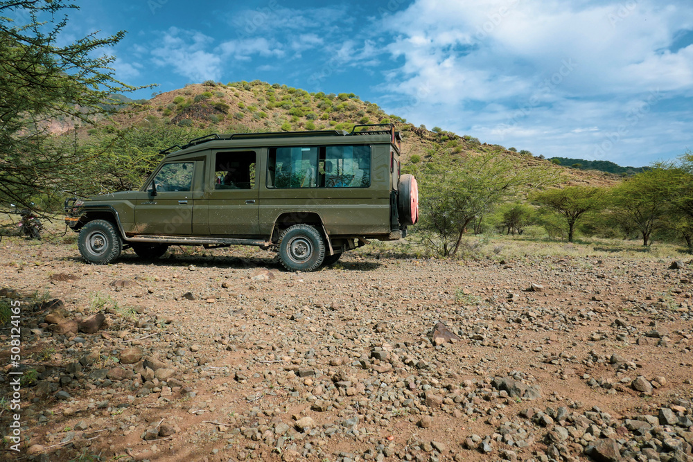 A safari vehicle in the wild against the background of Shompole Hills in Kajiado, Kenya