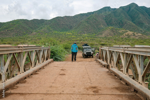 Rear view of a man on the bridge standing next to a safari van against Shompole Hill in Kajiado, Kenya
