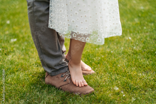 Father's Day. Happy family on a summer walk. Child and father together. feet barefoot on green grass. Healthy lifestyle. Father and daughter. Spring time. © sushytska