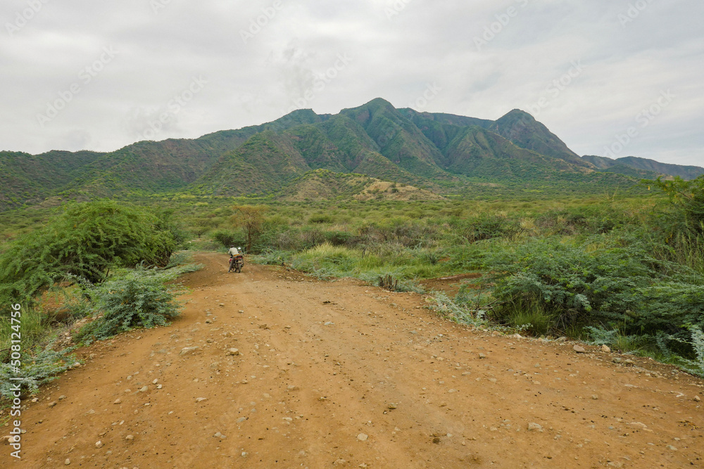 A man on a motorcycle against a mountain background at Shompole Conservancy, Kajiado County, Kenya A man on a motorcycle against a mountain background at Shompole Conservancy, Kajiado County, Kenya