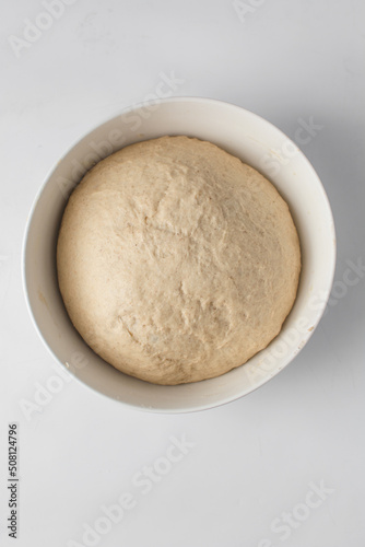 Dough that has doubled in size, dough that has risen, proofed dough in a white bowl