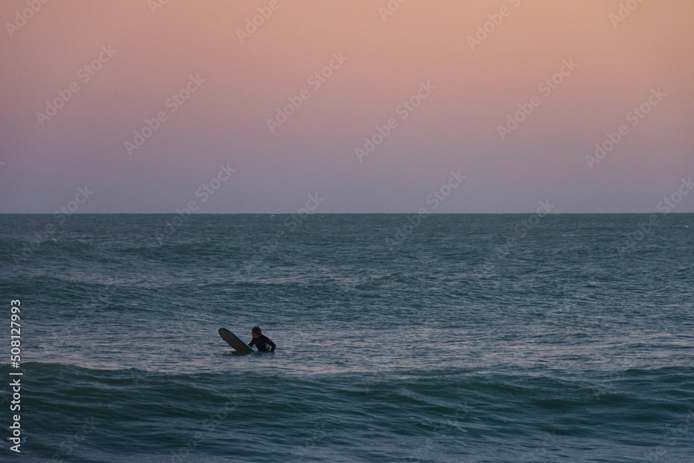 Surfer waiting for the wave during sunset