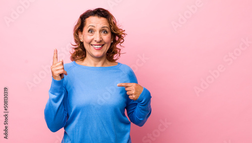 middle age hispanic woman feeling proud and surprised, pointing to self confidently, feeling like successful number one photo
