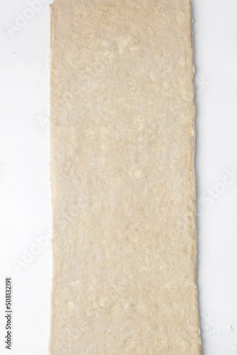 Pastry dough rolled out on a white background, stretched dough