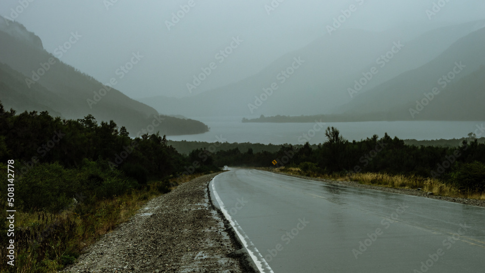 Route to a lake and a mountain range with a lot of fog on a rainy day