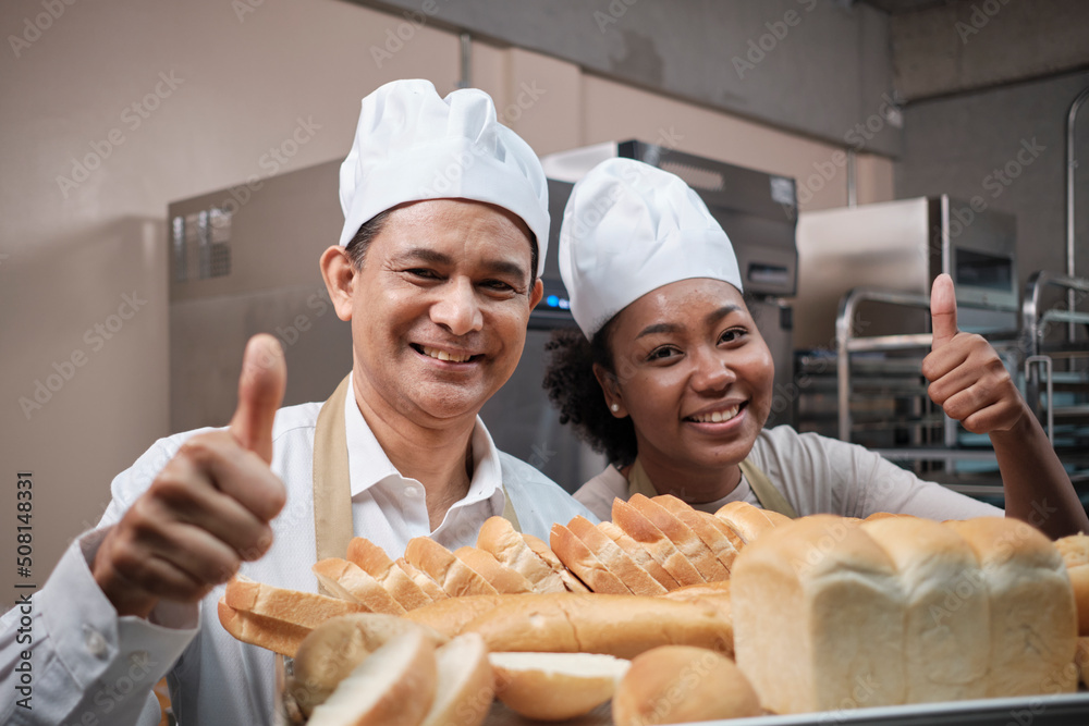 Portrait of professional chefs in white uniform looking at camera with ...