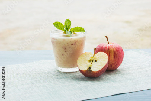 Apple smoothie with yogurt topped with mint leaves and halved apples placed on a cloth