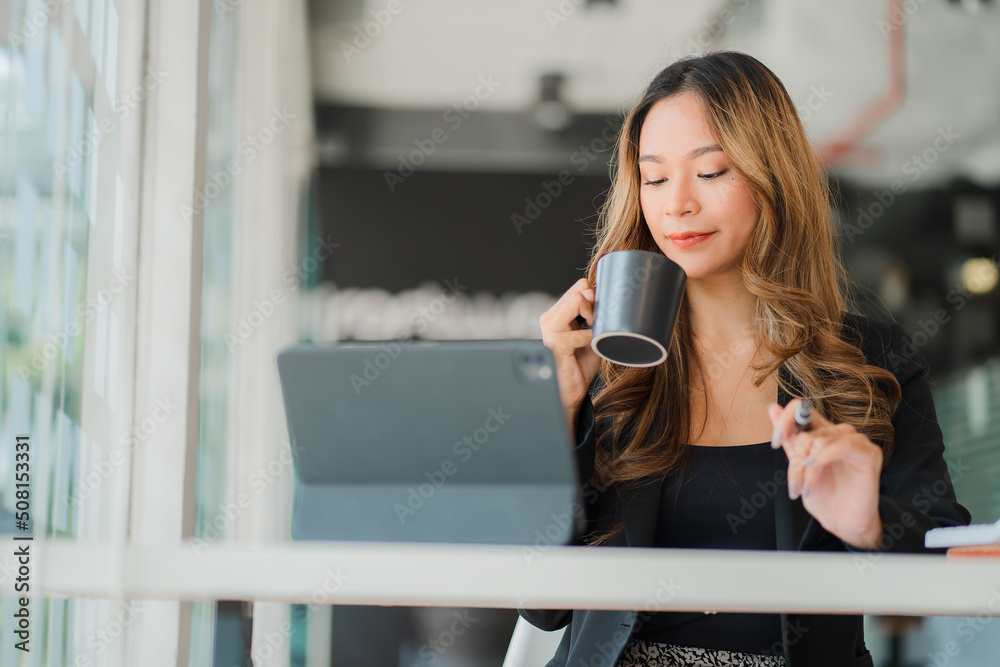 Asian businesswoman working with tablet at her desk with coffee in her spare time
