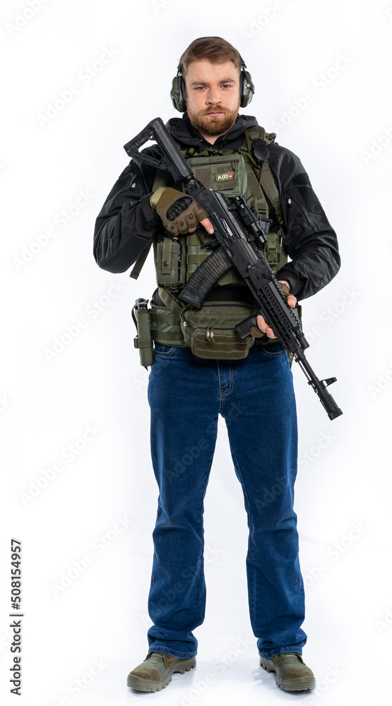 soldier, airsoft player in full gear with a machine gun. a man in headphones, a bulletproof vest, with a backpack and a full-length belt. White background. soldier, airsoft player in full gear with a machine gun. a man in headphones, a bulletproof vest, with a backpack and a full-length belt. White background.
