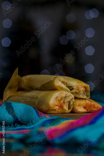 Rich red mole tamales, with meat, with a bokeh in the background, traditional Mexican food. Vertical photo.